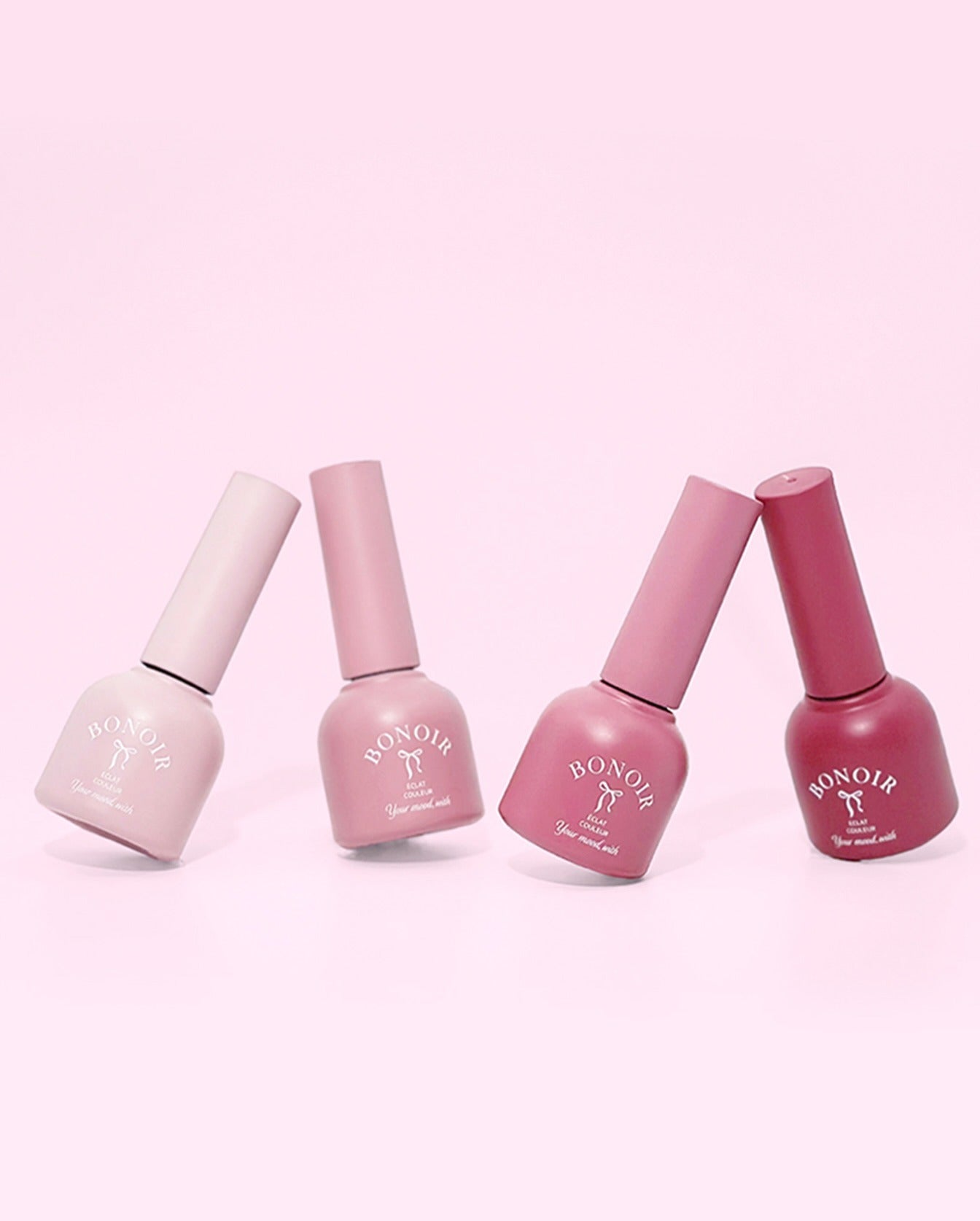 Four bottles of Bon Noir nail polish on a pink background