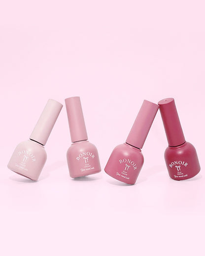 Four bottles of Bon Noir nail polish on a pink background