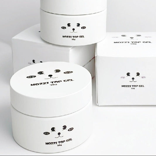 Two white containers with cartoon face designs and a box labeled 'MOZZI TOP GEL' on a light gray background.