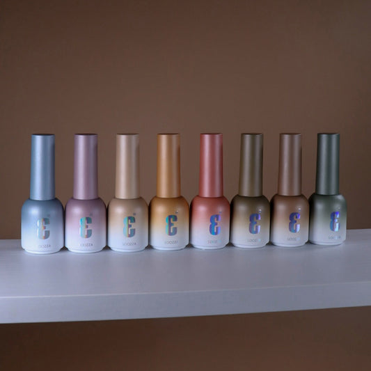 Row of Soozza nail polish bottles on a white surface with a brown background